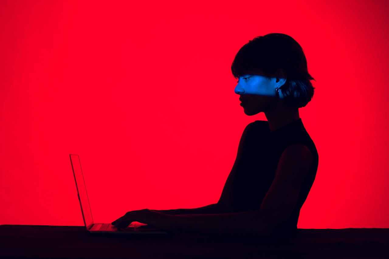 Customer searching on a laptop in dramatic red lighting,  represents customer journey